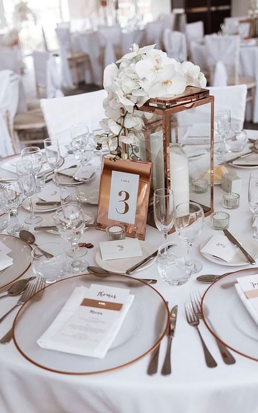 Eleganckie kompozycje kwiatowe i świece dodają uroku stołom podczas przyjęcia weselnego Eleganckie kwiaty i świece zdobią białe obrusy weselne